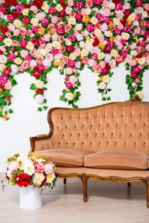 bouquet of beautiful summer flowers and vintage sofa over colorful flowers background