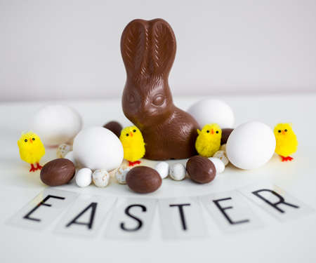 Easter background  - close up of eggs, chocolate bunny, sweets and Easter word on the tableの写真素材