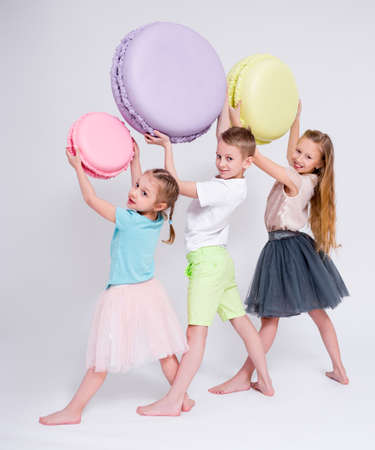 cute kids with big macaroons over white backgroundの写真素材