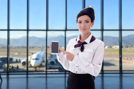 summer, vacation and travel concept - beautiful stewardess holding smart phone with blank screen in...