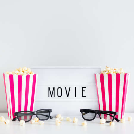 cinema and date concept - two red striped boxes with popcorn, 3d glasses and light box with movie...