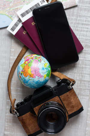 travel and vacation concept - close up of passports, tickets, map, smart phone and vintage camera on wooden tableの写真素材