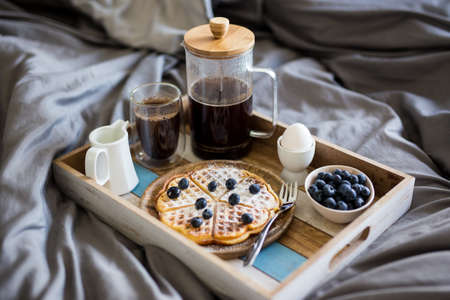 breakfast - close up of wooden tray with tasty food on the bedの写真素材