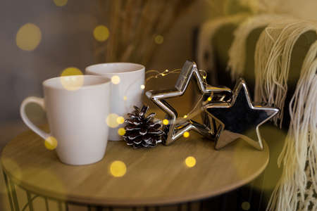 cozy winter background - close up of two tea cups, stars and fir cone on the tableの写真素材