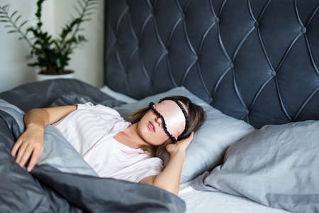 good morning concept - portrait of beautiful woman sleeping in bed with mask on her eyesの写真素材