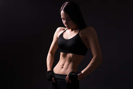 beautiful sexy girl with muscular body posing over black backgroundの写真素材