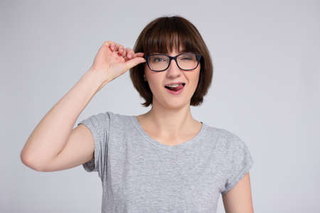 portrait of happy woman in eyeglasses with braces on teeth over gray background