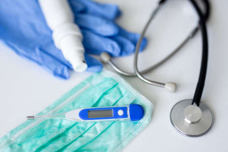 medicine, health care and pandemic concept - stethoscope, protective mask, gloves, sanitizer and thermometer over white table backgroundの写真素材