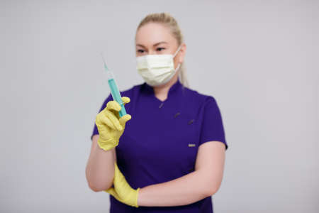 beauty injection concept - female nurse, cosmetologist or worker of beauty industry holding syringe over gray background with copy spaceの写真素材