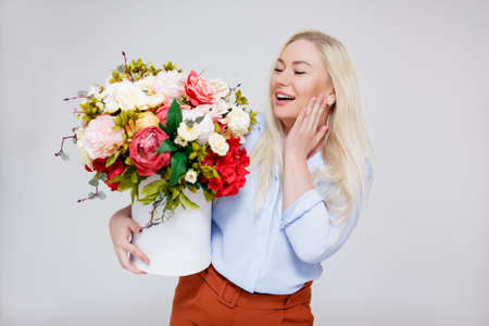 valentine's day or mother's day concept - portrait of surprised beautiful and elegant plus size blonde woman holding box with summer flowers over gray backgroundの写真素材