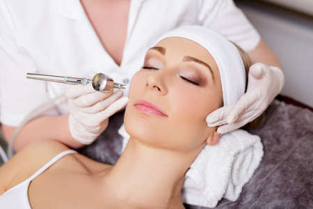 cosmetology and beauty concept - beautiful woman getting facial anti-aging procedure in beauty salonの写真素材