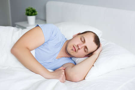 portrait of young man sleeping in bed at home