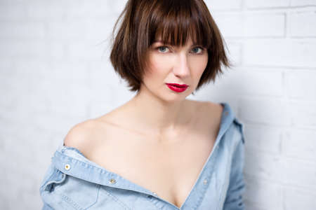 portrait of young sexy woman with red lips posing over white brick wall backgroundの写真素材