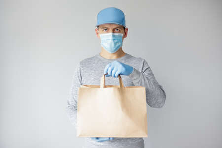 coronavirus concept - courier or food delivery man in medical mask over white background