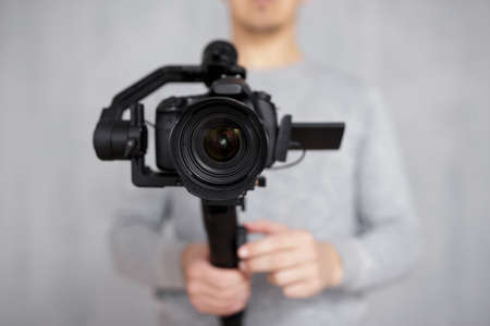 full length portrait of professional videographer with dslr camera on 3-axis gimbal isolated on white backgroundの写真素材