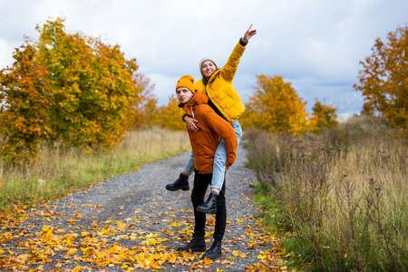 portrait of young couple having fun in autumn park with golden leaves