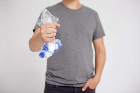 World Environment Day, recycling and reuse concept - man holding bag of plastic bottle caps for...