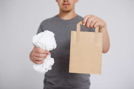 reduce, reuse and recycle concept - plastic bag and brown recyclable eco paper bag in male hands...