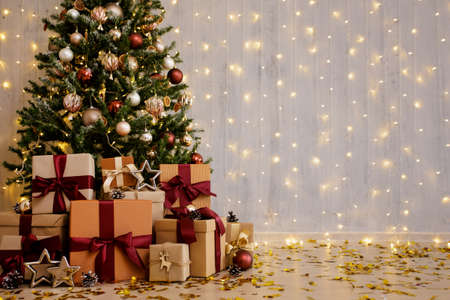 Beautiful decorated christmas tree and gift boxes with copy space over grey wall with lightsの写真素材