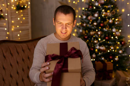 Christmas and magic concept - portrait of happy surprised young man opening gift box in decorated...