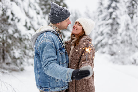 portrait of lovely couple posing with sparklers in winter forestの写真素材
