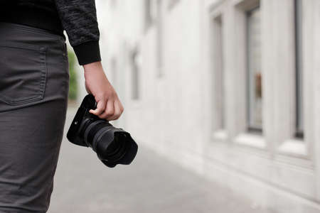 photography and hobby concept - modern dslr camera in male hands, copy space over concrete building backgroundの写真素材