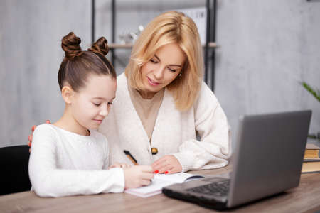 school, homework and distance education concept - portrait of happy school girl doing homework with her mother at homeの写真素材