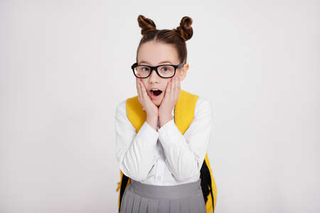 portrait of cute surprised or amazed girl in school uniform and eyeglasses over white background with copy spaceの写真素材