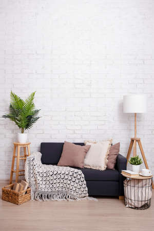 Sofa, lamp, table and plants with copy space over brick wall