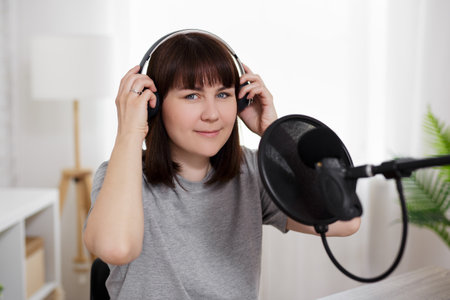 podcast and blogging concept - young woman preparing for podcast recording with microphone and...