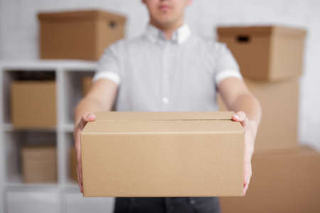 postal delivery concept - close up of man giving a box in warehouse or post officeの写真素材