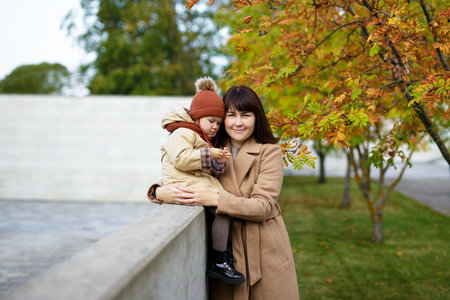 portrait of young attractive woman posing with his little daughter in autumn parkの写真素材