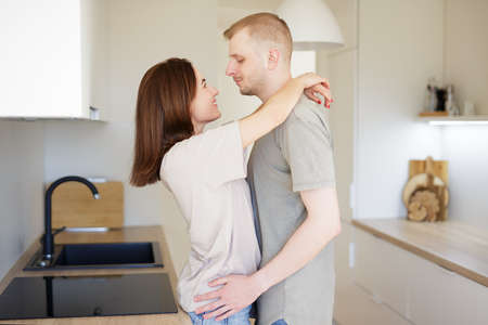 love and relationship concept - portrait of happy couple in love hugging in modern kitchen