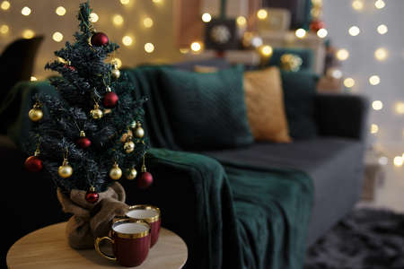 home interior with small decorated christmas tree and coffee cups