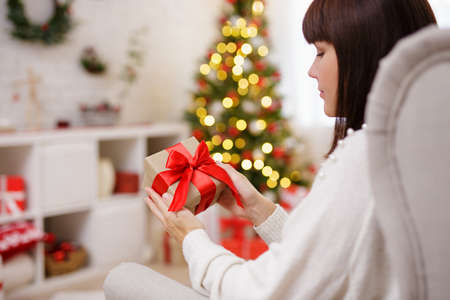 Young woman holding christmas gift with red ribbon