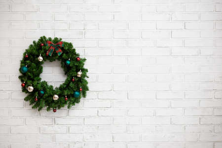 close up of Christmas wreath and copy space over white brick wall background