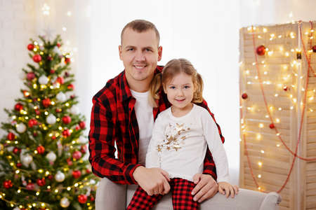 Happy father and daughter posing in christmas decorated roomの写真素材