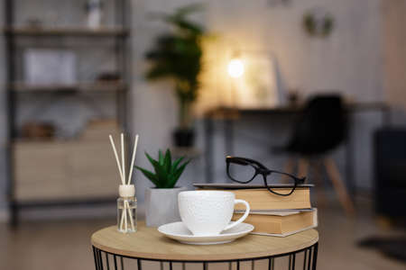 reed diffuser, cup of tea or coffee and books on table in living room or officeの写真素材