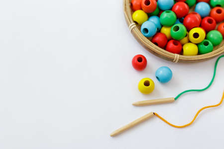toy for motor skills development - colorful wooden beads, lace and needle over white background with copy spaceの写真素材