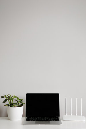 Laptop, router and green plant on white table with copy spaceの写真素材