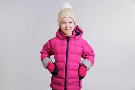 Portrait of happy little girl in winter wear on grey background