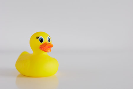 Yellow funny bath duck on white table with copyspace