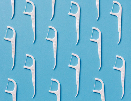 Pattern of white dental floss with a plastic toothpick on blue backgroundの写真素材