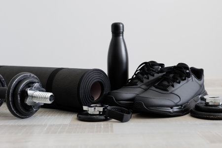 Fitness theme with dumbbells, sports mat, shoes and water bottle on wooden floorの写真素材
