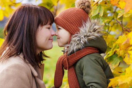 close up portrait of happy mother and his little daughter in autumn parkの写真素材