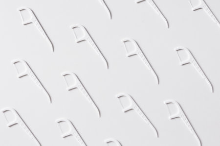 Pattern of white dental floss with a plastic toothpick on white backgroundの写真素材