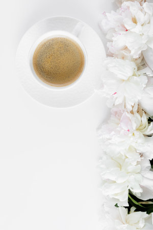 Beautiful white peonies and cup of coffee on white tableの写真素材