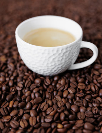 White ceramic cup of dark coffee on background from coffee beans