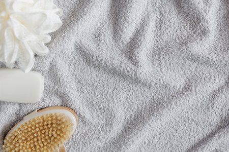Top view of grey towel, sponge, soap and massage brush with copyspace