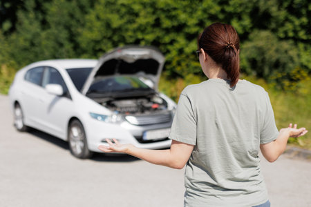 Shocked girl is standing near the open hood of the car